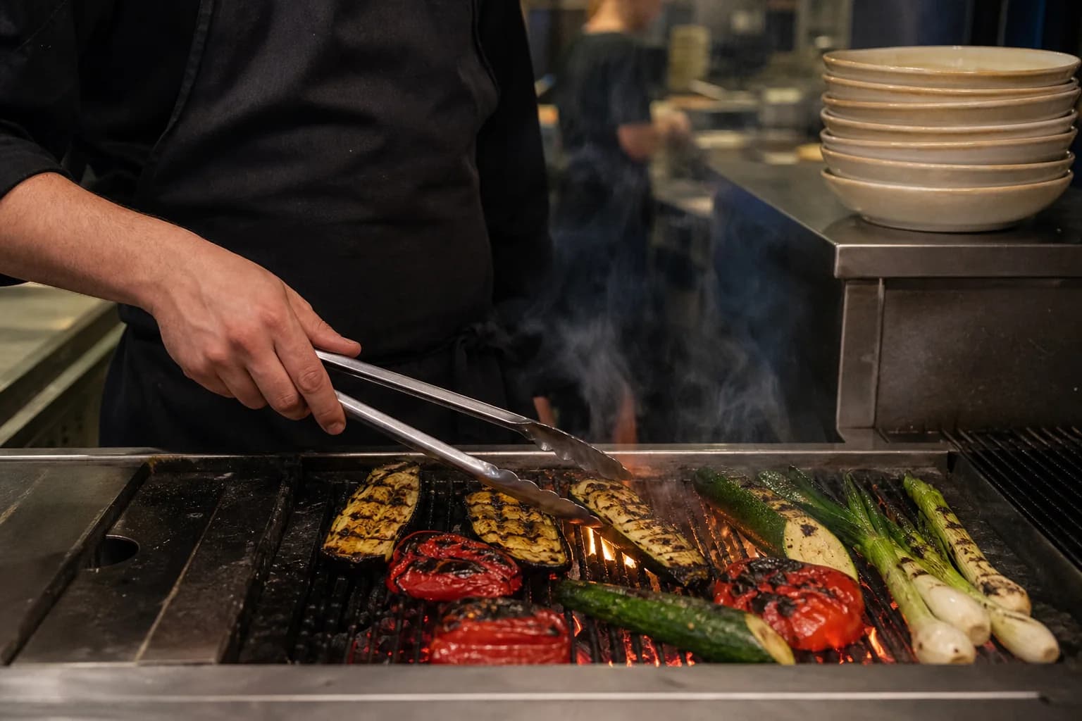 Chef grilling seasonal vegetables over charcoal in the Linden Table kitchen